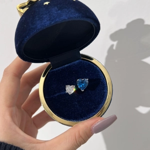 Close-up of heart-cut blue and white zircon earrings in a navy blue velvet jewelry box