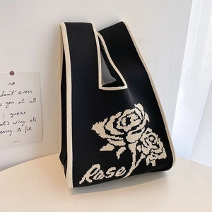 Detail of a chic black and white knitted tote bag with a woven rose pattern and Rose text
