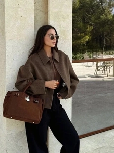 Close-up of a vintage brown wool jacket with zipper detail worn with a matching handbag