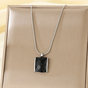 Close-up of black square cut gemstone pendant on a silver snake chain necklace