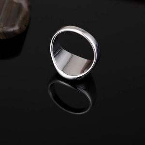 Chevalière hexagonale en acier inoxydable argenté poli sur une surface noire réfléchissante