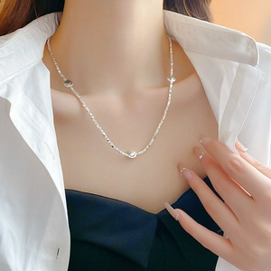 Minimalist silver smiley face pendant necklace worn on a classic white shirt for women