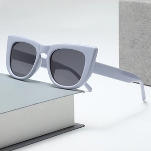 Retro cat-eye light blue sunglasses with dark grey lenses on a minimalist stone display