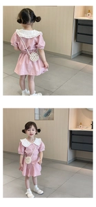 Detail of a pink textured cotton girl's dress with white ruffled collar and pearl woven bag