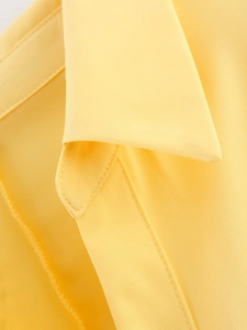 Detail of a bright yellow lapel shirt showing fine twill fabric texture and sewing lines