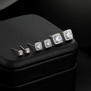 Detail view of six pairs of square halo stud earrings with brilliant round center stones