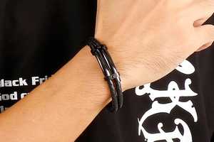 Gros plan d'un bracelet en cuir tressé noir pour homme avec un fermoir en métal poli