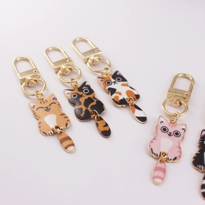Cartoon enamel cat keychains with gold metal hooks on white background, assorted colors