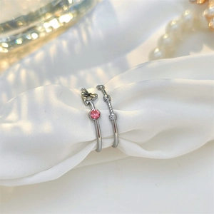 Detailed view of silver minimalist rings with pink zircon and star on white silk cloth