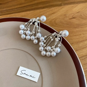 Detailed view of silver tassel pearl earrings with fringe design on ceramic plate
