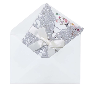 Detail of silver glitter laser-cut floral wedding invitation with a white ribbon bow