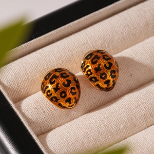 Macro view of leopard print enamel earrings with golden metallic finish in jewelry box