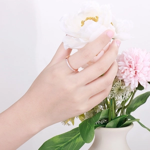 Nahaufnahme eines minimalistischen Rings in Roségold mit Zirkonia beim Berühren von Pfingstrosen