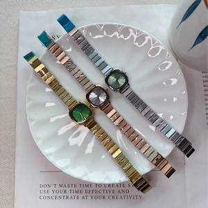 Detailed view of three quartz watches with square cases and metal links on a ceramic plate