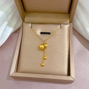 Close-up of golden gourd pendant necklace with small gold beads in a gift box
