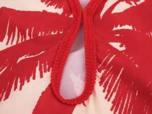 Close-up of red braided trim and tropical palm leaf print on summer vacation dress