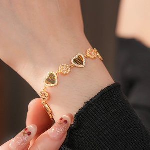 Detailed close-up of 18K gold plated bracelet with zircon hearts and starburst charms