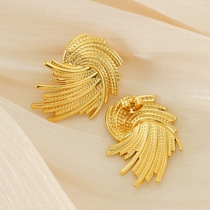 Detailed view of gold fan-shaped stud earrings with textured radial pattern on silk