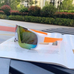 Outdoor shot of sports cycling sunglasses with white frame and orange temples on magazine