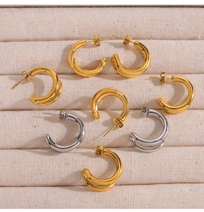 Flat lay of double-layered geometric C-shape earrings in gold and silver steel finish