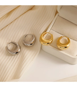 Detailed view of glossy gold and silver thick waterdrop earrings on jewelry box