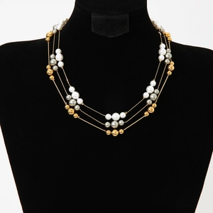 Three-layer luxury pearl and gold bead necklace displayed on a black velvet mannequin