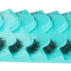 Detailed close-up of 10 pairs of dense curly black half false eyelashes on blue tray