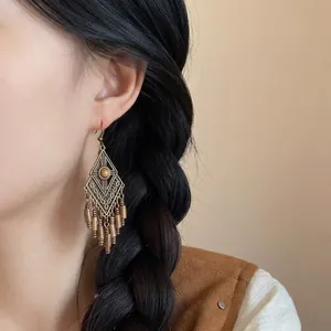 Boucles d'oreilles bohèmes vintage en bronze avec longues franges métalliques sur modèle