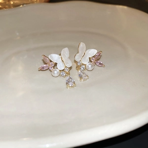 Detail of bow-shaped pearl earrings with pink zircon and crystal drop on ceramic tray