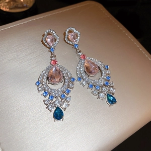 Close-up of vintage fan-shaped drop earrings with colorful crystals and silver plating