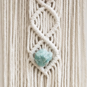 Handmade macrame wall hanging featuring natural turquoise stone and ivory cotton rope details