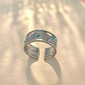 Detail of silver multi-layered open ring with blue gemstones and star patterns