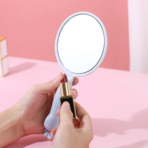 Light blue hand mirror with cute rabbit ears being used by a model for makeup