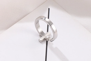 Detailed close-up of a silver stainless steel cross ring with brushed metal texture