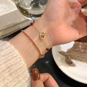 Détail d'un ensemble de bracelets plaqués or 18 carats avec perles rouges et breloque