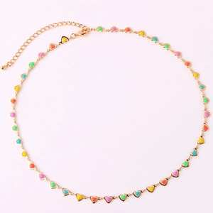 Detailed view of gold chain necklace with colorful enamel heart charms on pink background