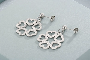 Close-up of silver hollow heart-shaped hoop earrings on a light blue surface