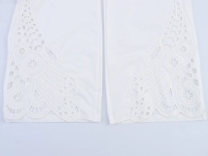 Détail macro de broderie anglaise blanche complexe sur le haut sans manches et le pantalon