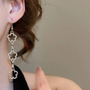Close-up of silver long-drop earrings with three hollow flower links on a female model