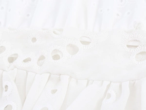 Close-up of white cotton fabric with intricate hollow-out floral embroidery details