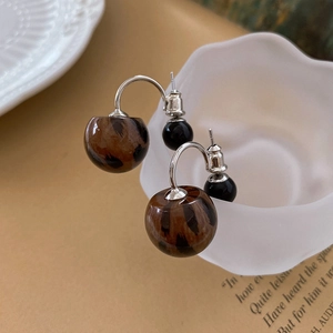 Detail view of leopard print double ball earrings on a white decorative plate