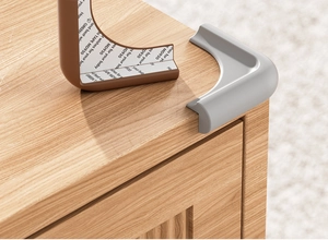 Macro detail of L-shaped silicone baby safety corner guard with adhesive tape on wood