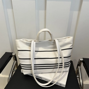 Large capacity striped canvas tote bag for women placed on an urban style book