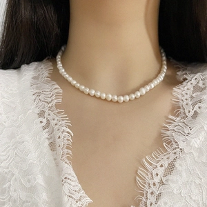 Close-up of elegant freshwater pearl choker worn by a model against white lace