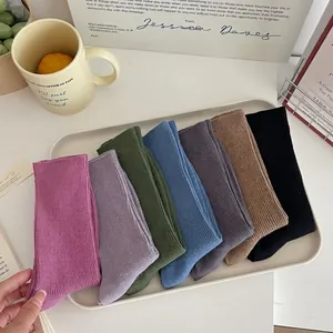 Set of seven solid color cotton crew socks in muted tones on a minimalist white tray