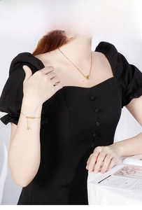 Detail of gold heart pendant necklace and matching bracelet set on elegant black dress