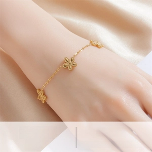 Close-up of gold plated stainless steel bracelet with beaded flower charms on model