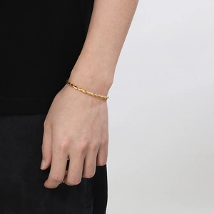 Macro shot of gold twisted rope cuff bracelet with high-end polished metal texture