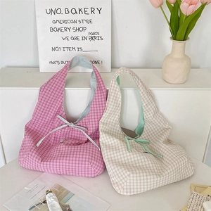 Detailed view of plaid tote bags with decorative ribbon bows in a stylish lifestyle setting