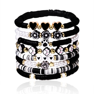 Detailed view of multilayered clay bracelets with heart, flower and yin yang charms